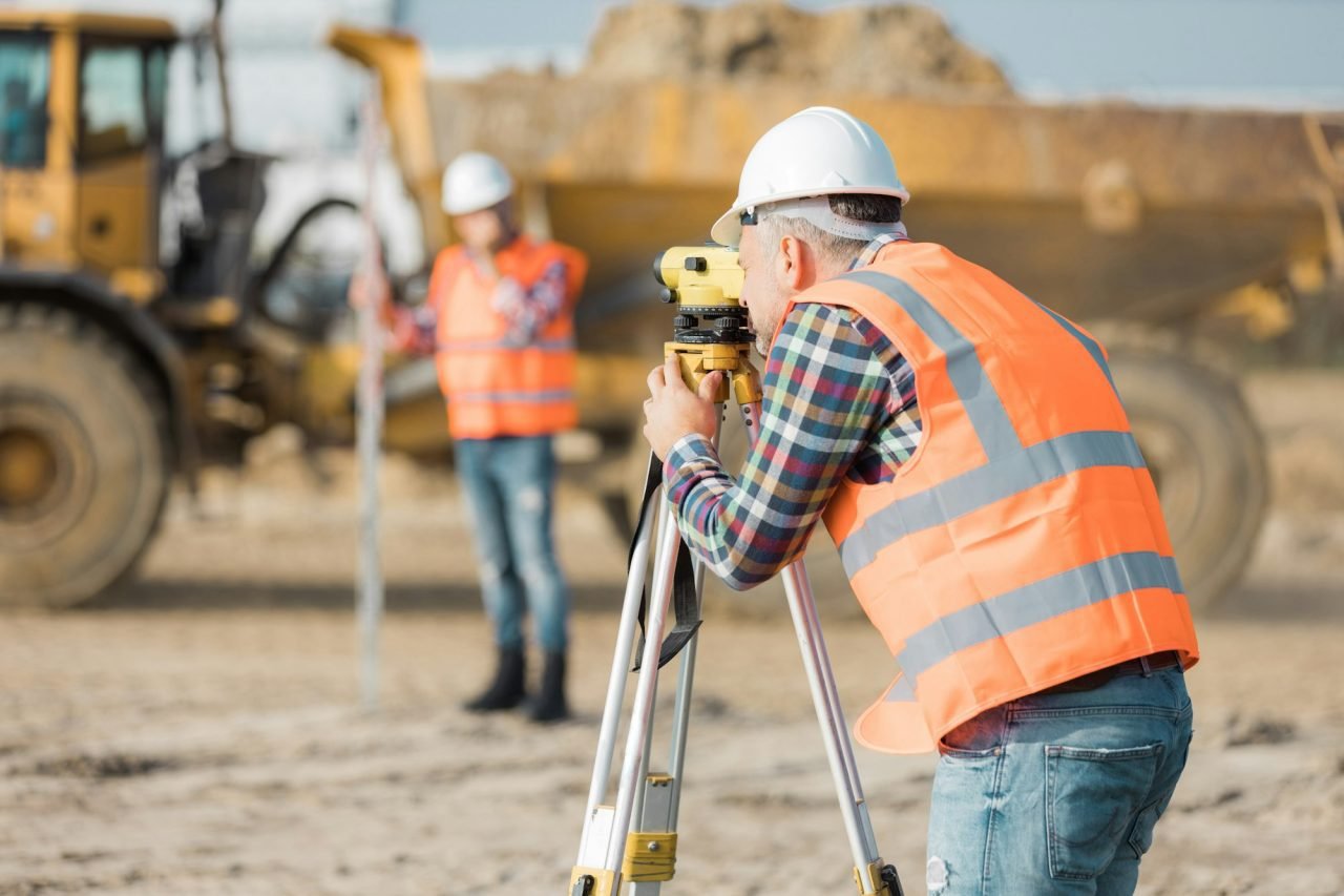 two-road-construction-workers-using-measuring-device-on-the-field.jpg